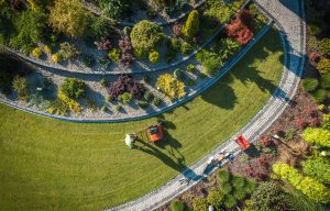 Aerial View of Professional Garden Worker with Push Spreader. Lawn Fertilizing Theme. Gardening and Landscaping Industry.